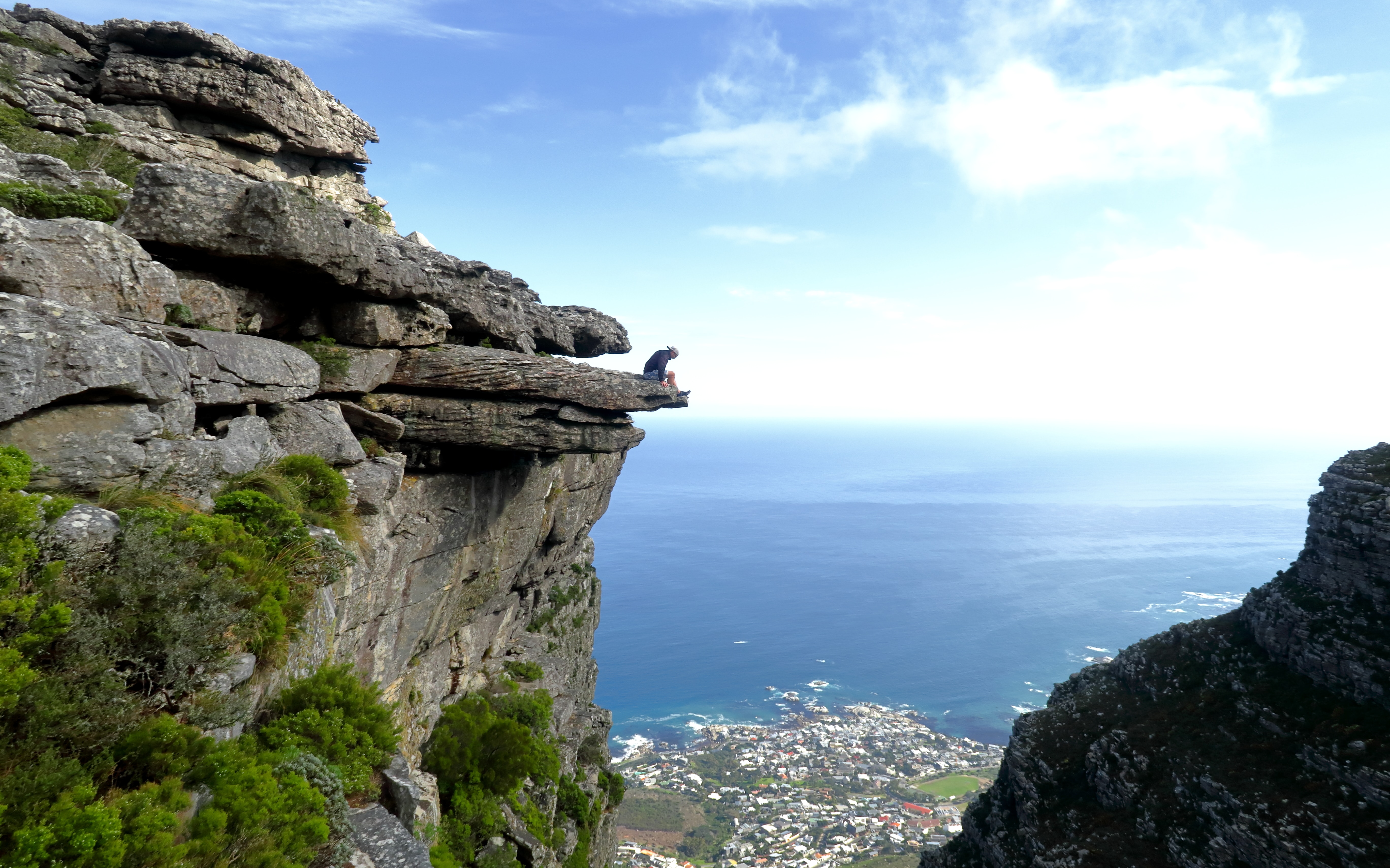 Man sitting precariously over cliff